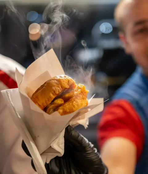 A hot burger being handed over the counter