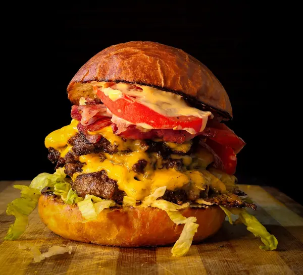 A tall stacked burger with cheese and bacon